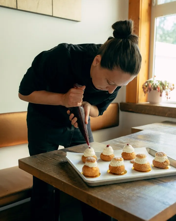 Baker piping cream on choux pastry