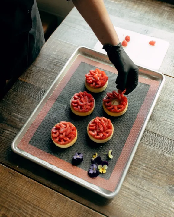 Strawberry tarts being plated with edible flowers